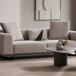 A modern textured fabric Nova Sofa featuring deep seating cushions, adjustable plush backrest pillows, channel-tufted wide armrests, and sleek low-profile metal legs in a minimalist room interior.