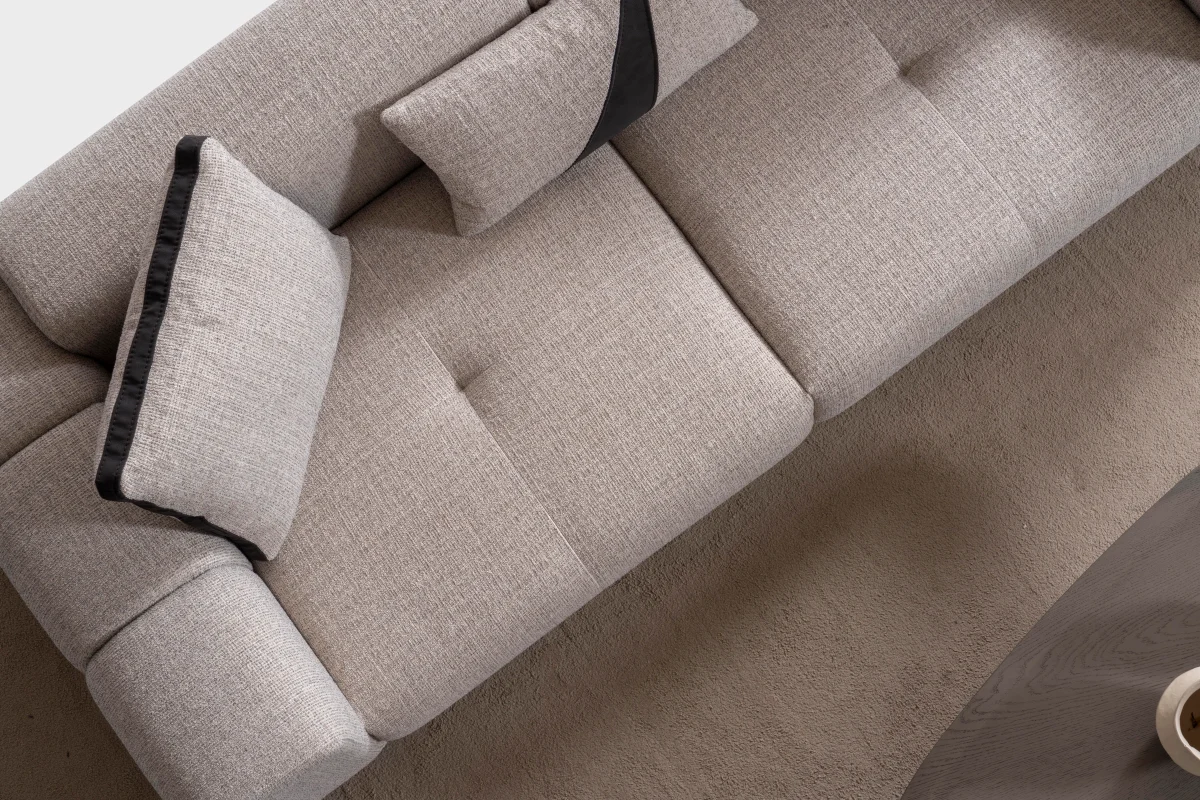 A modern textured fabric sofa featuring deep seating cushions, adjustable plush backrest pillows, channel-tufted wide armrests, and sleek low-profile metal legs in a minimalist room interior.
