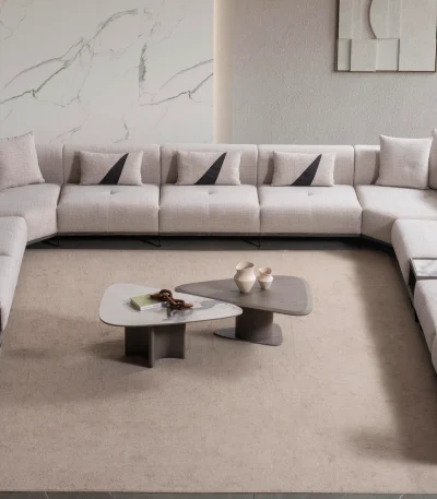 An extra-large U-shaped modular sectional sofa featuring expansive seating, plush backrest cushions, geometric accent pillows, and integrated tray console modules in a luxurious modern interior.